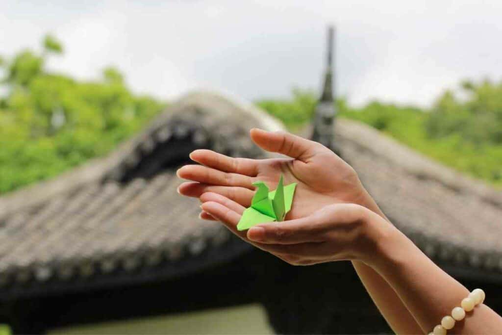 Green origami crane in woman's hand